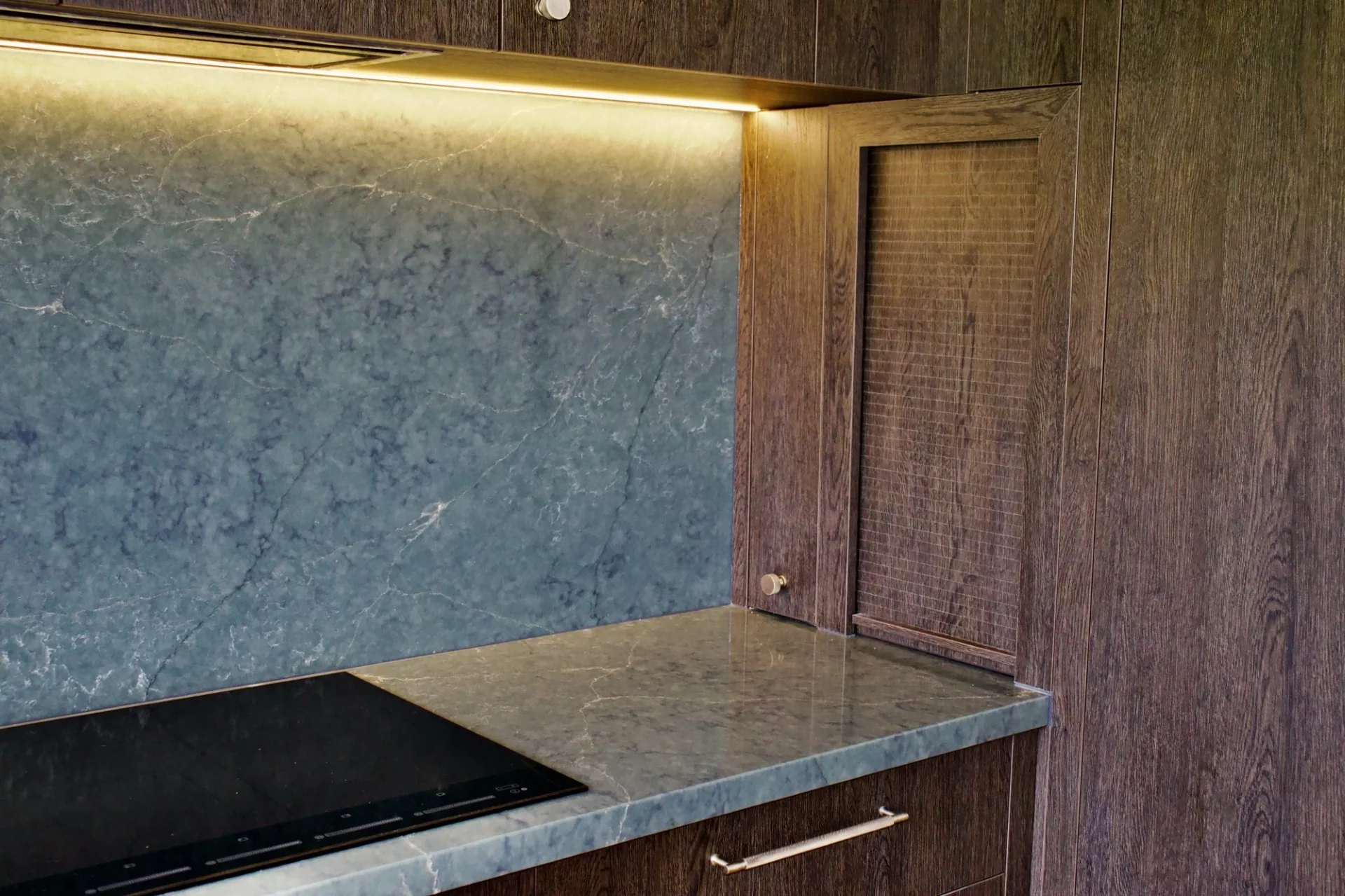Minimalist kitchen with dark timber cabinetry and stone benchtop
