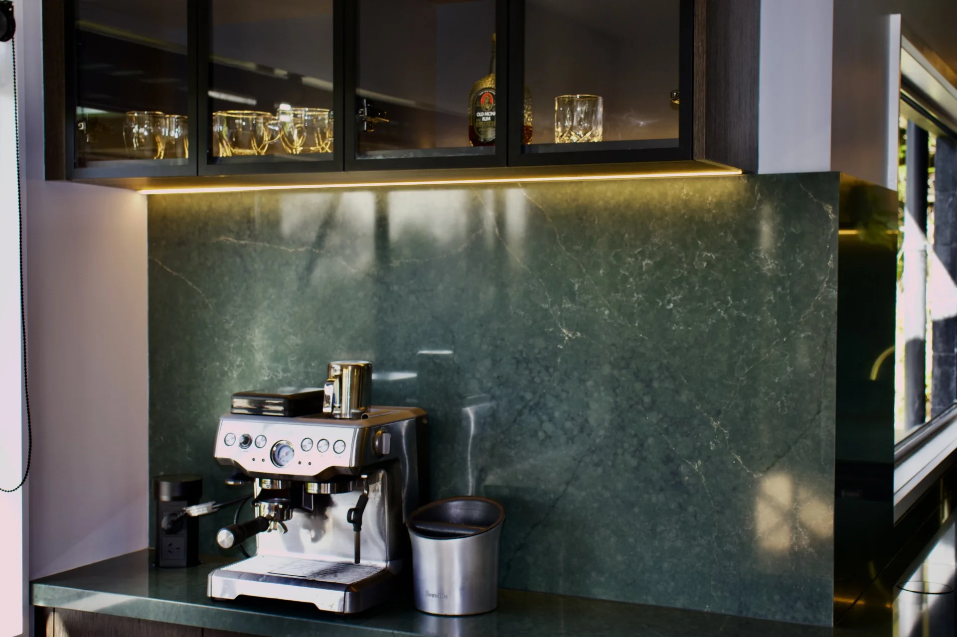 Kitchen material detail with stone surface, timber cabinetry, and warm lighting